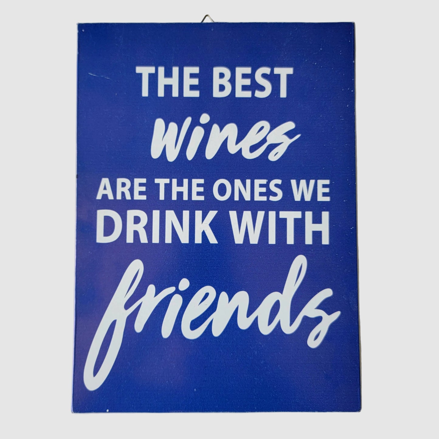 blue wall sign with white text that reads, 'THE BEST wines ARE THE ONES WE DRINK WITH friends,'