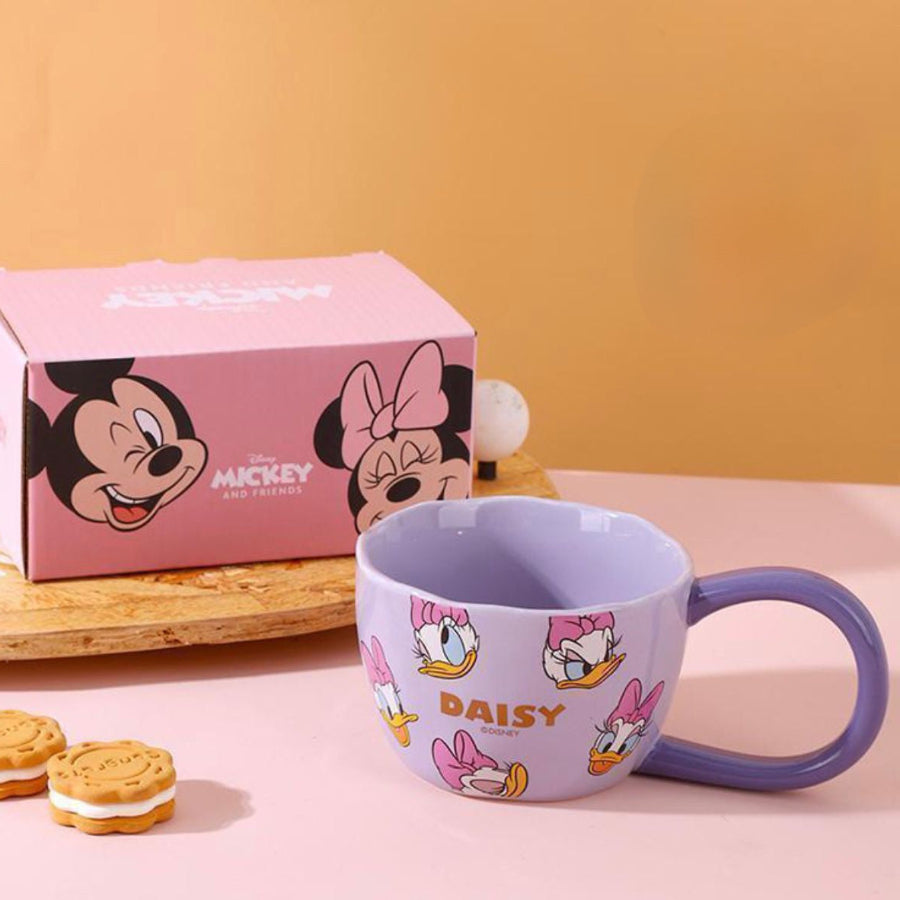 Disney mug with Daisy Duck design next to a pink gift box on a pink background