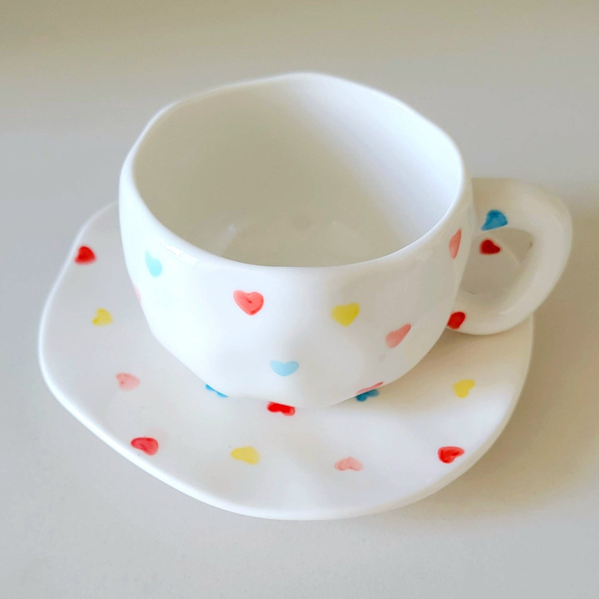 White teacup and saucer with colorful heart 