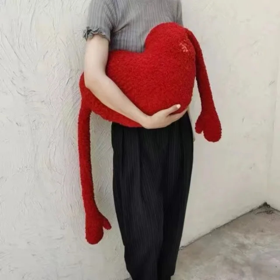 Person holding a large red heart-shaped pillow.