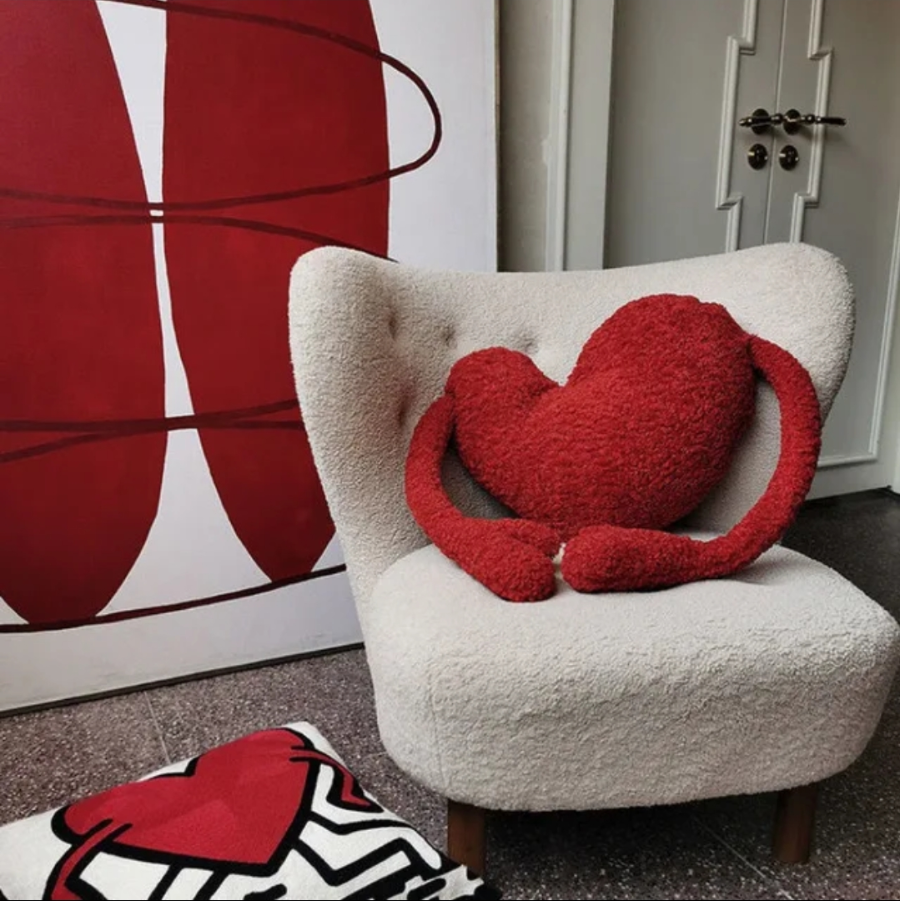 Red heart-shaped pillow on a white armchair 