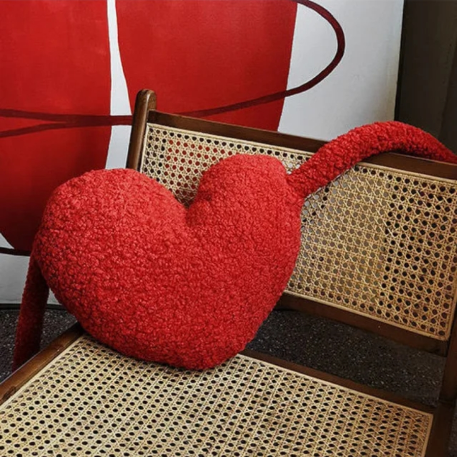 Heart-shaped red pillow on a wicker chair